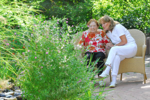 Foto einer Bewohnerin mit Mitarbeiterin in unserem Garten.